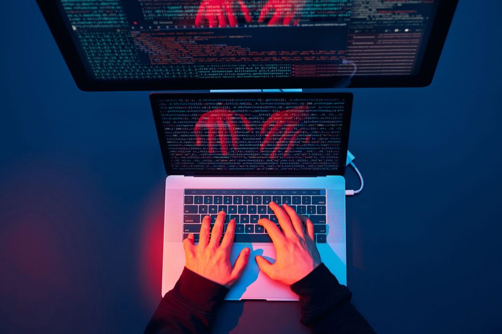 someone typing on a laptop with a lot of visible code